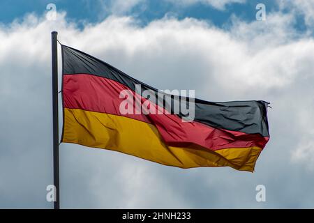 Im berühmten Reichstagsgebäude, dem Sitz des Deutschen Bundestages, winken deutsche Flaggen im Wind an einem sonnigen Tag mit blauem sk Stockfoto