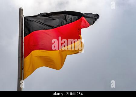 Im berühmten Reichstagsgebäude, dem Sitz des Deutschen Bundestages, winken deutsche Flaggen im Wind an einem sonnigen Tag mit blauem sk Stockfoto