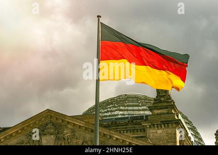 Im berühmten Reichstagsgebäude, dem Sitz des Deutschen Bundestages, winken deutsche Flaggen im Wind an einem sonnigen Tag mit blauem sk Stockfoto