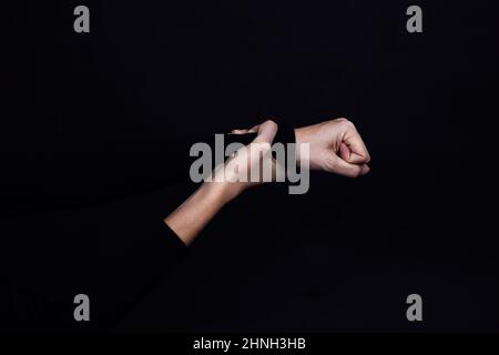 Kaukasische Hand, die geballte Faust hält, um jemanden auf schwarzem Hintergrund zu missbrauchen. Häusliche Gewalt. Kopieren Sie den Raum physischen und psychischen Missbrauch Stockfoto