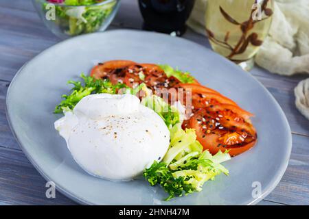 Frischer Salat mit Burrata, Salat und Tomaten. Köstlicher italienischer Käse aus Mozzarella und Rahm Stockfoto