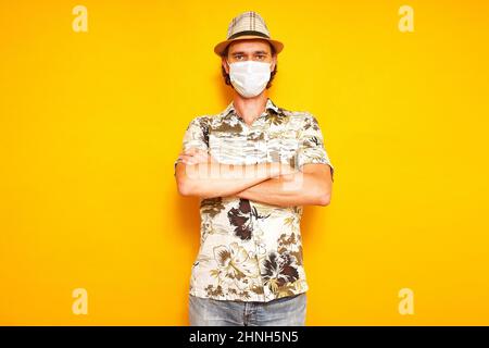 Männlicher Touristenreisender in medizinischer Maske steht mit gekreuzten Armen auf seiner Brust mit ernsthafteren Blick. Stockfoto