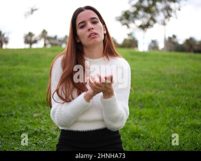 Eine junge Frau im Park klatschte sarkastisch und schaute unglücklich auf die Kamera. Stockfoto