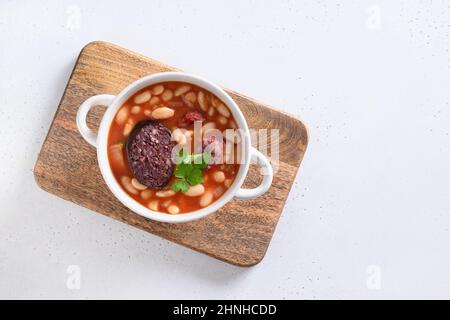 Traditionelle spanische Fabada mit Haricot, Morcilla, Tomatenmark, Chorizo auf weißem Hintergrund. Blick von oben. Speicherplatz kopieren. Stockfoto