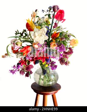 Die Kunst der Blumenarrangements. Bouquet von bunten Gartenblumen auf weißem Hintergrund isoliert. Die Komposition umfasst Tulpen, Narzissen, Allium, M. Stockfoto