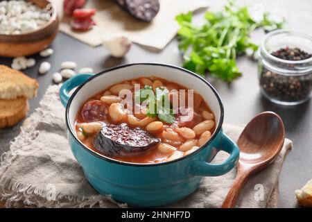 Asturiana traditionelle Eintopf Fabada mit Harikot, Tomaten, Blutwurst auf braunem Tisch. Nahaufnahme. Stockfoto