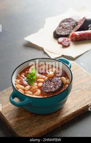 Asturiana fabada mit Haricot, Blutwurst auf braunem Hintergrund. Vertikales Format. Nahaufnahme. Traditionelles spanisches Abendessen. Stockfoto