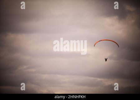 Bild eines Gleitschirms, der alleine fliegt, gegen einen grau bewölkten Himmel. Stockfoto