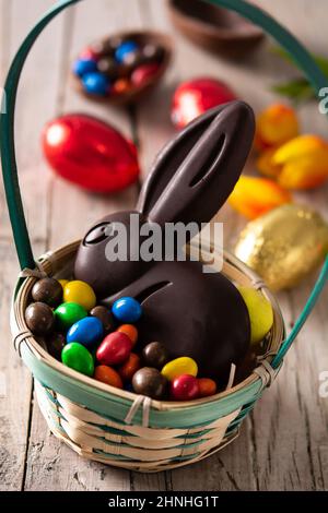 Osterschokoladenhase und bunte Eier auf Holztisch Stockfoto