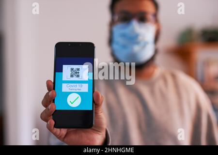 Covid19 Tracking-App, die von einem Mann mit einer chirurgischen Maske gehalten wird Stockfoto
