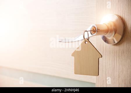 Schlüssel mit Schlüsselbund in Form Haus in Türschloss.mit hellem Sonnenlicht Stockfoto