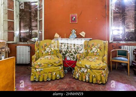 Februar 2022, Schlafzimmer mit Kamin und Sesseln in perfektem Zustand in einem verlassenen Haus, Urbex in Norditalien. Erkundung der Städte Stockfoto