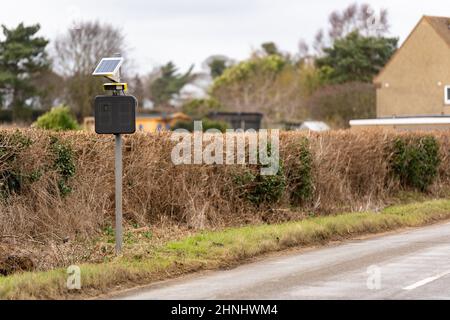 Solarbetriebene Geschwindigkeitsfalle, die eine Kennzeichenerkennung eingebaut hat, um Menschen zu fangen und zu verfolgen, die durch ein Dorf auf dem Land Rasen Stockfoto