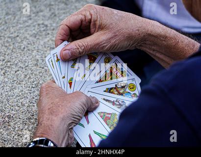Nahaufnahme der Hände, die ein Kartenspiel mit spanischen Karten spielen. Stockfoto
