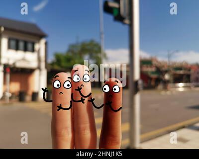 Drei Finger sind als drei Personen dekoriert. Zwei Personen diskriminieren ihren Freund. Stockfoto