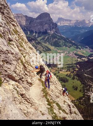 Diese Gruppe junger Erwachsener befindet sich am letzten Anflug zur Brücke über die Schlucht auf dem letzten Abschnitt des Klettersteiges Klettersteig Brigata Tridentina geschützter Klettersteig, der zum Rifugio Pisciadu in der Sellagruppe unweit des Grödner Jochs einführt Die italienischen Dolomiten von Südtirol. Stockfoto