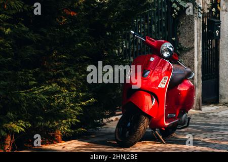 Ca. 2022: Motorradespa parkte auf dem Bürgersteig bei Sonnenuntergang in Sofia, Bulgarien. Wunderschöne orangefarbene Landschaft. Hochwertige Fotos Stockfoto