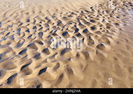 Abstraktes Sandmuster im Morgenlicht am Strand Stockfoto