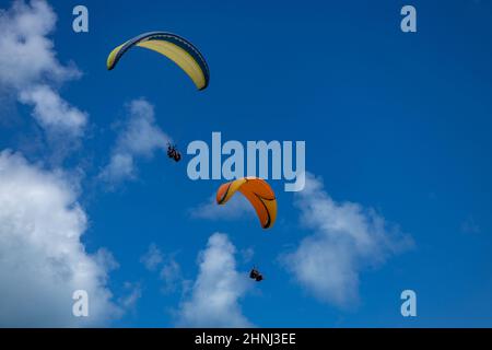 Zwei ausgestellte Gleitschirme fliegen hoch am Himmel. Sport mit hohem Risiko. Stockfoto