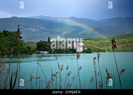 Regenbogen über dem Toblino See und seiner Burg. Madruzzo, Provinz Trient, Trentino-Südtirol, Italien, Europa. Stockfoto