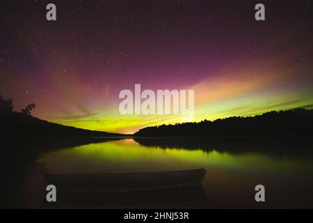 Nachthimmel-Ästhetik, Nachthimmel mit Aurora Borealis im Hintergrund, schöner Blick bei einer Roadtrip, Boot auf dem Wasser schwimmend Stockfoto