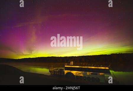 Nachthimmel-Ästhetik, Nachthimmel mit Aurora Borealis im Hintergrund, schöner Blick bei einer Roadtrip, Boot auf dem Wasser schwimmend Stockfoto