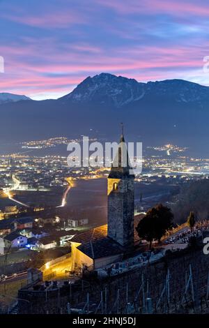 Die mittelalterliche Kirche von San Giorgio und die unterliegende Stadt Pergine. Im Hintergrund der Berg Becco di Filadonna. Serso, Trentino, Italien. Stockfoto