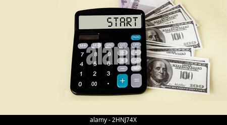 Starttext auf der Taschenrechner-Anzeige mit Dollarnoten auf weißem Hintergrund Stockfoto