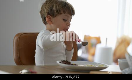 Kleinkind Essen allein während der Mittagspause Baby mit Utensil Stockfoto