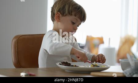 Kleinkind Essen allein während der Mittagspause Baby mit Utensil Stockfoto