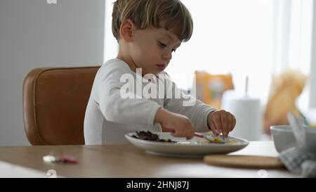 Kleinkind Essen allein während der Mittagspause Baby mit Utensil Stockfoto