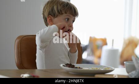Kleinkind Essen allein während der Mittagspause Baby mit Utensil Stockfoto