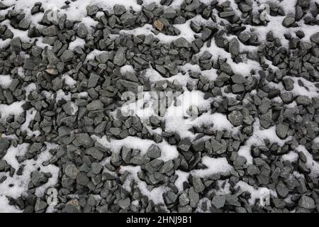 Dunkelgrauer Kies im Schnee. Toller Hintergrund für Ihr Design Stockfoto