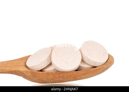 Mehrere medizinische Tabletten mit einem Holzlöffel, Makro, isoliert auf einem weißen Hintergrund. Stockfoto