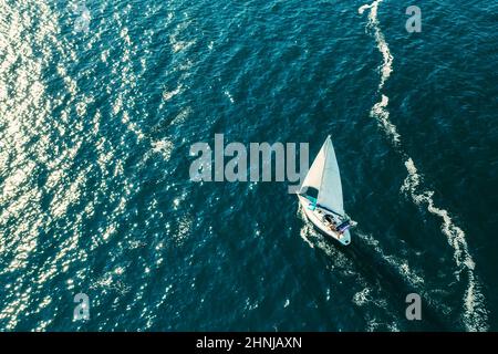 ROVINJ, TSCHECHISCHE REPUBLIK - JULI 03 2021: Segelschiff hinterlässt weiße Schaumspuren auf der Oberfläche des Adriatischen Meeres. Helles Sonnenlicht, das von der Oberfläche des ruhigen, vom Meer ergreifenden Wassers reflektiert wird. Luftaufnahme Stockfoto