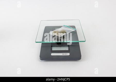 Zwei Gramm getrocknete medizinische Marihuanaknospen in einem klaren Plastikbeutel auf einer Skala auf einem weißen Studiohintergrund. Cannabisblütenstamm, Hazy Kush Marihuana f Stockfoto
