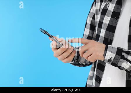 Mann im Hemd hält Telefon auf blauem Hintergrund Stockfoto