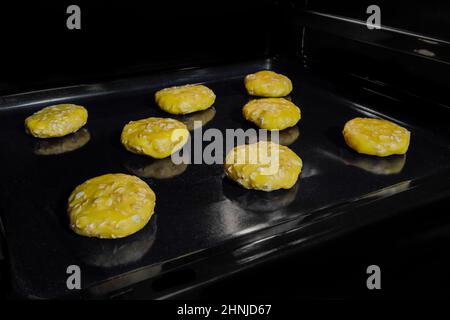 Acht ungekochte Haferflocken auf Metallblech im Ofen Stockfoto