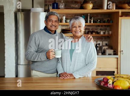 Porträt eines glücklich pensionierten älteren Birazialpaares, das zu Hause gesund lebt. Stehen in der modernen Küche. Stockfoto