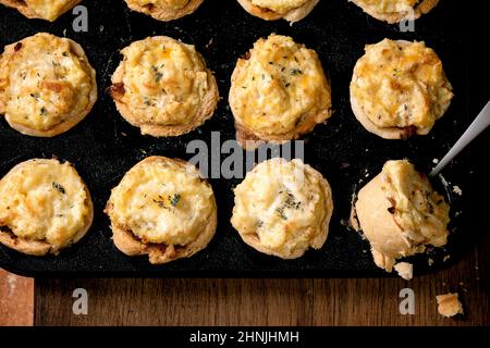 Traditionelle Hackfleisch Mürbeteig Mini-Pasteten mit Kartoffelpüree und Thymian in schwarzem Backblech auf Holzhintergrund. Rezept für ein Abendessen zu Hause. Flat la Stockfoto