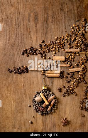 Aromatische Gewürzkollektion als Weihnachtskugeln Formen sich auf Weihnachtsbaum aus verschiedenen Kaffeebohnen auf dunklem Holzhintergrund. Weihnachten Grüße Kaffee l Stockfoto