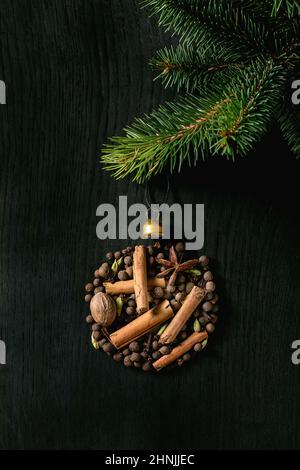 Aromatische Gewürzkollektion, Glühwein-Zutaten als Weihnachtskugel mit Tannenbaum. Piment, Zimtstangen, Kardamom, Nelke, Muskat über bla Stockfoto