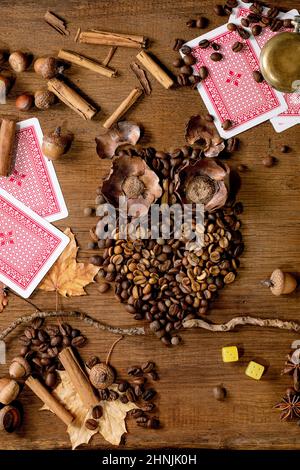 Eulenform aus Kaffeebohnen und Gewürzen. Eule sitzen auf dem Ast mit Spielkarten, würfeln auf Holzhintergrund. Lustige Geheimnis Kaffee Vorhersage Konzept Stockfoto