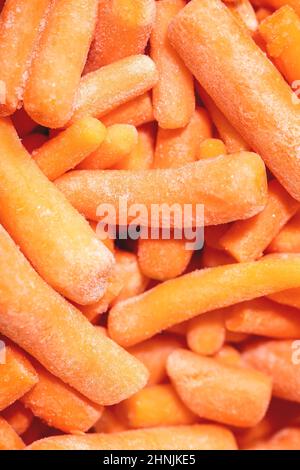 Haufen gefrorener geschälter roher Bio-Baby-Karotte. Lebensmittelhintergrund, Makro, Nahaufnahme. Draufsicht Stockfoto