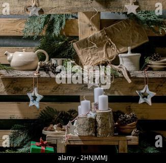 Weihnachtliche Mode rustikaler Stil Wohneinrichtung mit handwerklichem Holz, Keramik und Geschenkschachteln mit Adventskerzen auf alten Holzpaletten-Regalen als Backgr Stockfoto