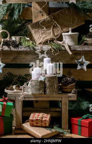 Weihnachtliche Mode rustikale Einrichtung mit handgefertigtem Holz, Keramik und Geschenkschachteln mit Adventskerzen auf alten Palettenregalen aus Holz als BA Stockfoto