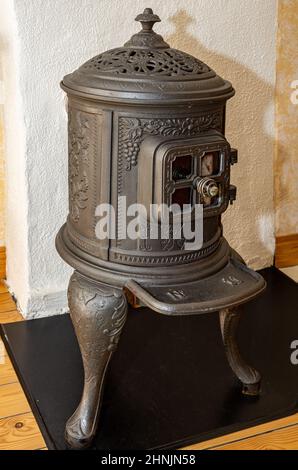 Klassischer traditioneller rustikaler Gusseisenofen vor einer weißen Wand. Stockfoto