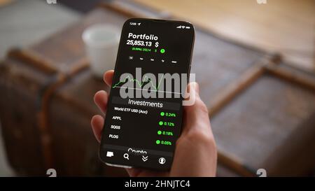 Hand Holding Phone mit Trading-App Mockup Beobachtung des Aktienmarktes und der steigenden Investitionen in Dollar Stockfoto