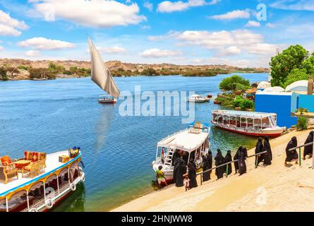 Arabische Damen in der Nähe der Boote am Ufer des Nils, Assuan, Ägypten Stockfoto