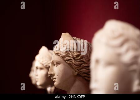 Nahaufnahme von antiken Frauenstatuen auf rotem Hintergrund Stockfoto